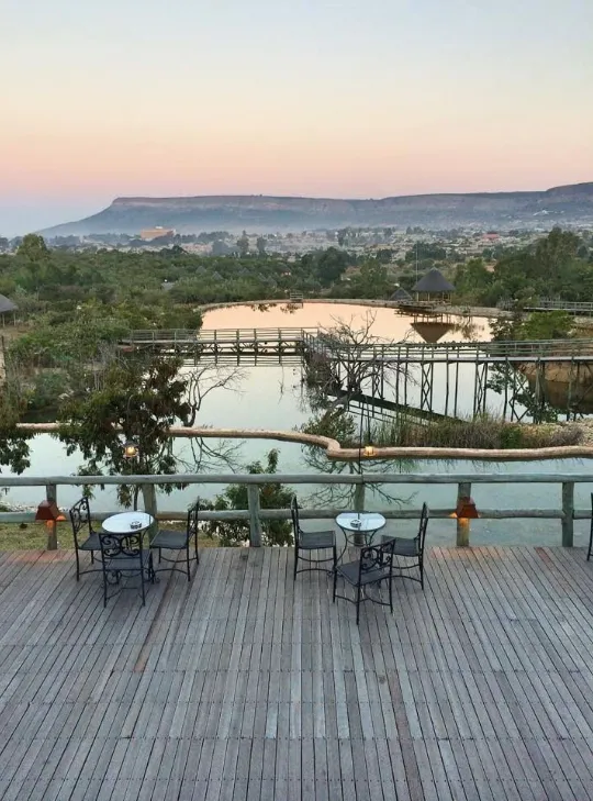 Deck de madeira com mesas, virado para os lagos e passadiços, ao fim da tarde